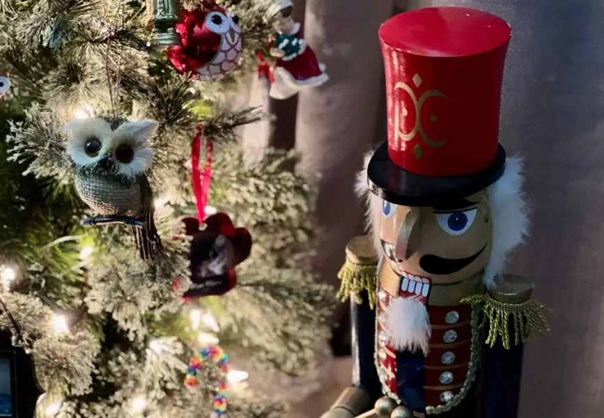 A nutcracker standing next to a white-lighted Christmas tree.